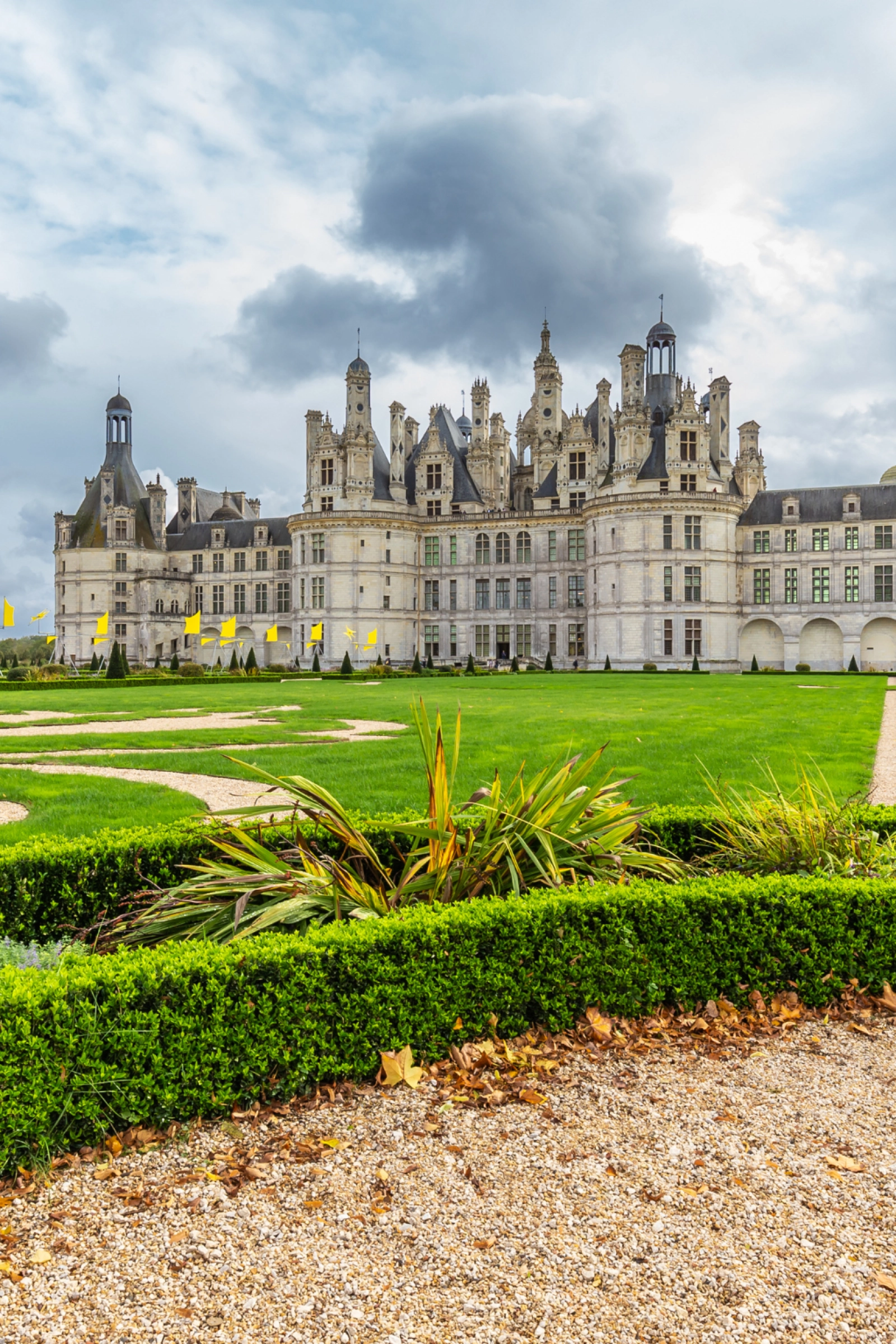 Château de Chambord in the Loire Valley, with formal gardens in the foreground and stormy skies above—symbolizing the grandeur and elegance of the region.