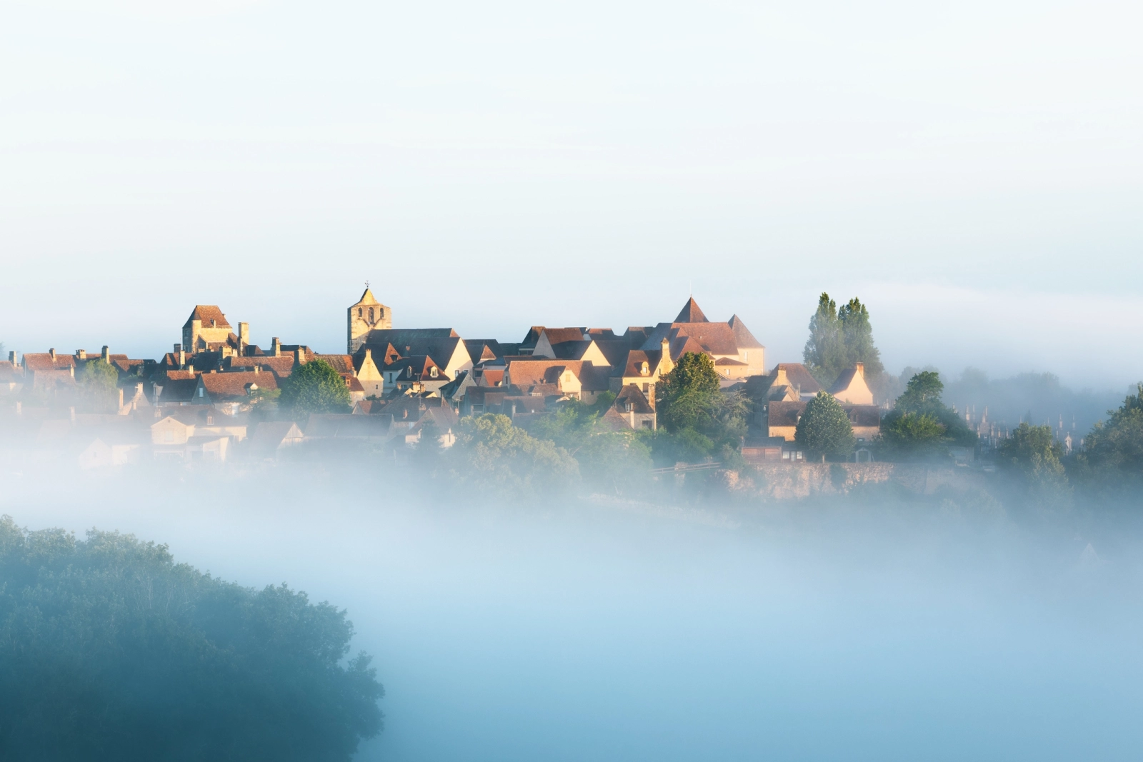 Golden hilltop village in the Dordogne emerging from morning mist – evoking timeless beauty, perfect for slow luxury travel through France’s most charming hidden regions.